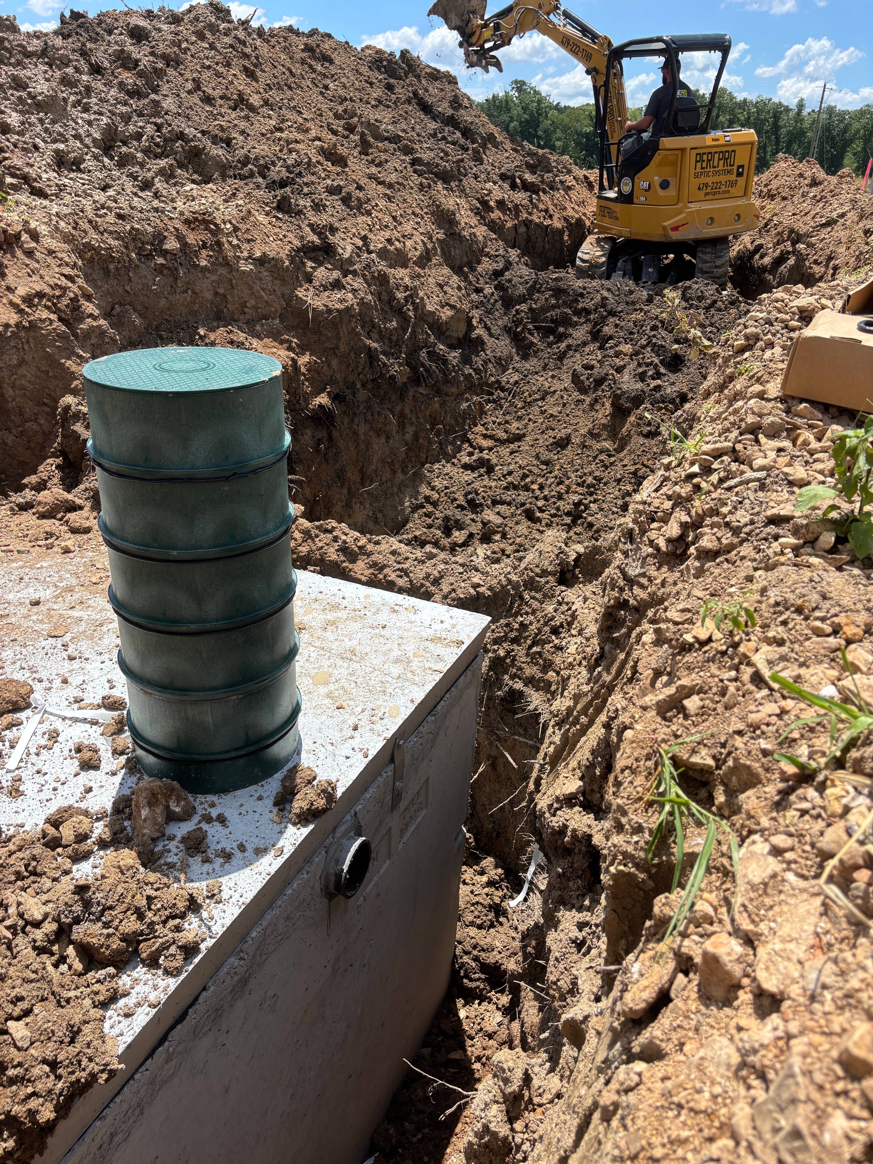 Excavator lifting concrete manhole